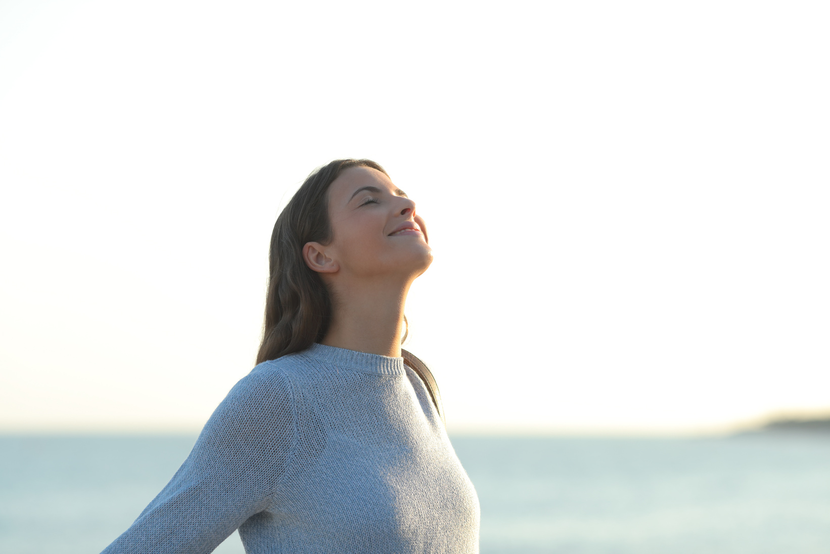 Happy girl breaths fresh air on the beach